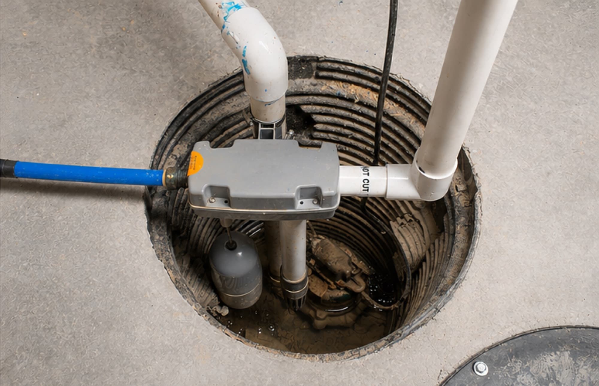 A sump pump installed in a basement pit with discharge piping