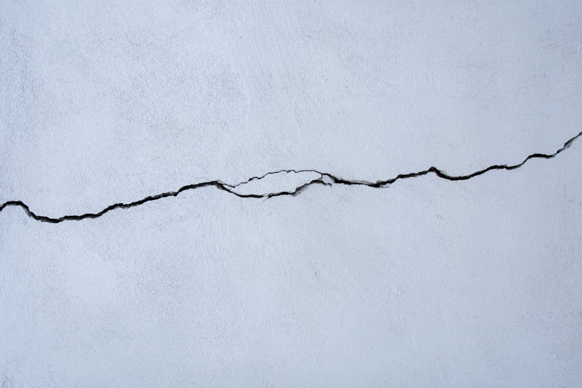 A single diagonal crack running across a pale interior basement wall